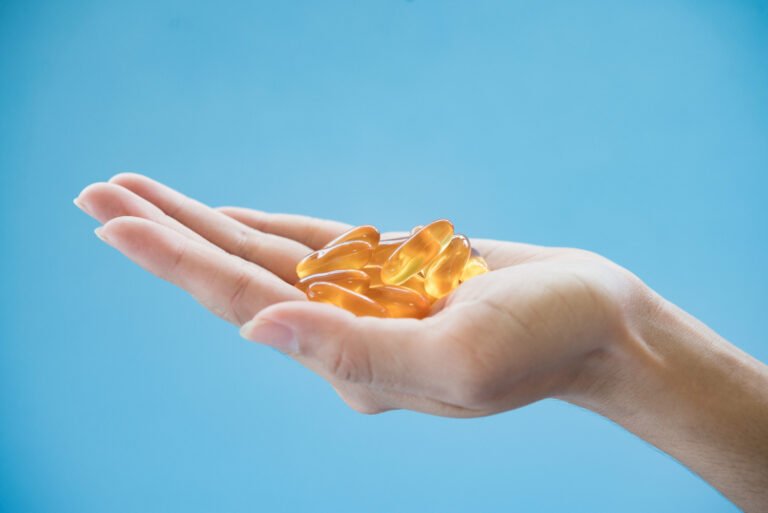 Hand holding orange gel capsules